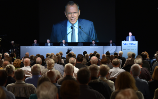 Grosse Leinwand mit Podium und Gästen. 