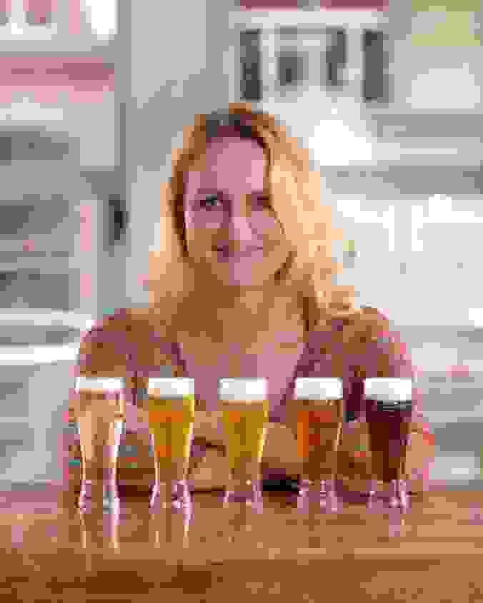 Portrait von Carmen Wyss mit fünf Biergläser vor sich. 