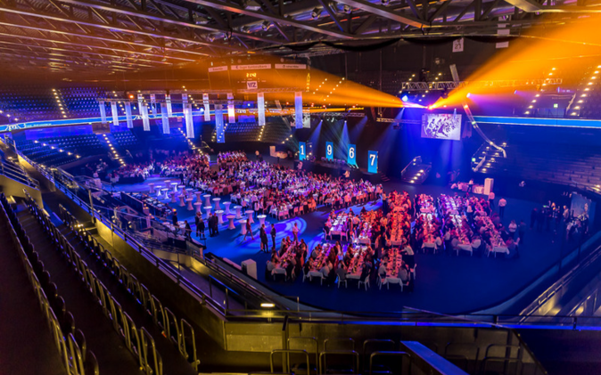 Festlich dekorierte Halle mit schöner Stimmung, Gäste sitzen an den Tischen. 