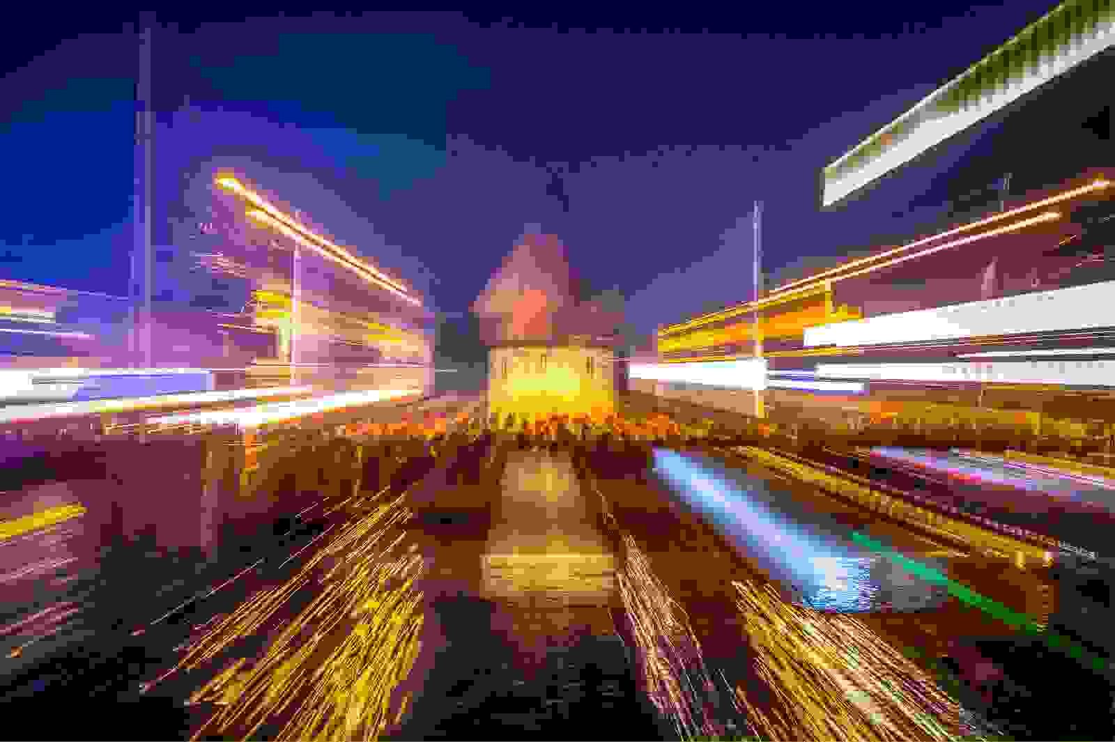 Nachtaufnahme vom Wasserturm mit vielen Leuten. 