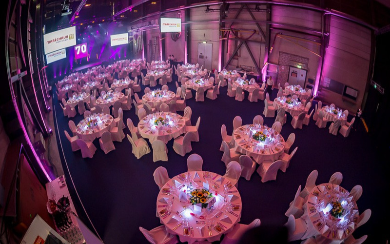 Jubiläum Maréchaux Elektro Feierlich hergerichtete Werfthalle. Runde Tische ohne Gäste.