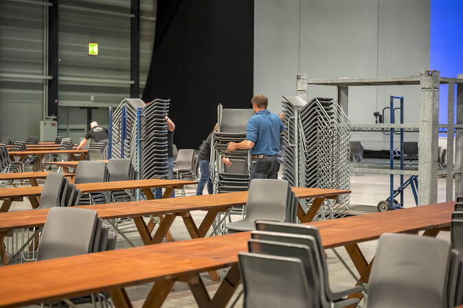 Helfende räumen Stühle zusammen. 