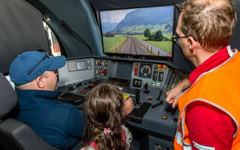 Lokführer und zwei Gäste mit Sicht aus einer Lokomotive am 10-jährigen Jubiläum.