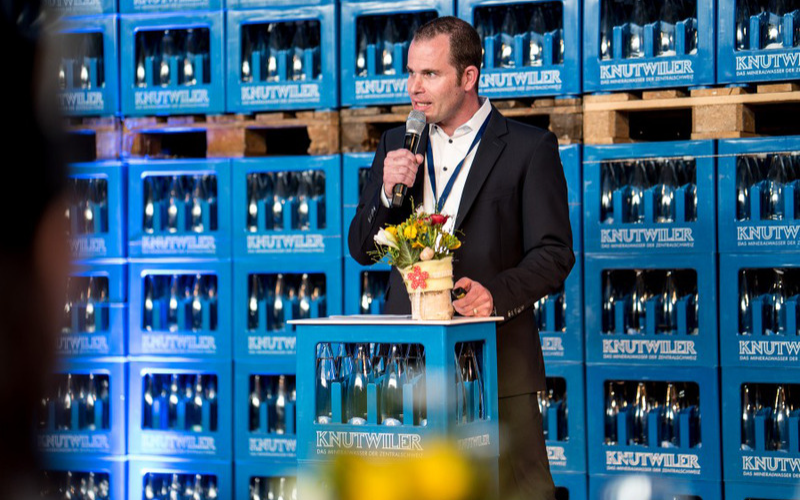 Jubiläum Mineralquelle Bad Knutwil Sprecher am Rednerpult aus Knutwiler-Harassen, Hintergrund aufgestapelte Knutwiler-Harassen.