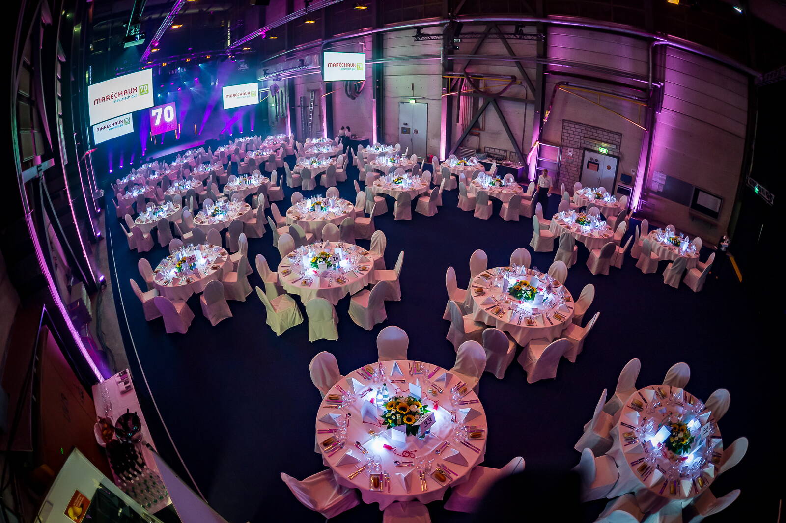 Jubiläumsanlass Maréchaux Elektro Feierlich hergerichtete Werfthalle. Runde Tische ohne Gäste.