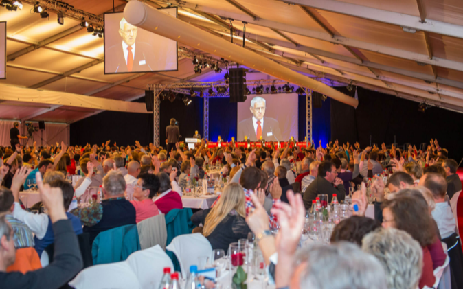 Festzelt mit Leinwand und Gästen. 