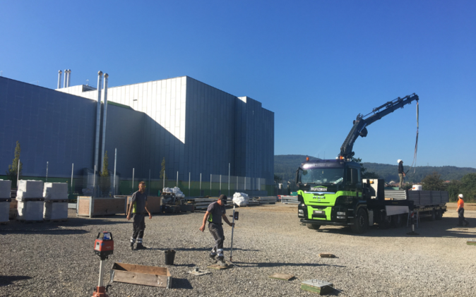 Kiesplatz beim Start des Aufbaus eines Anlasses, Lastwagen mit Kran, Helfer