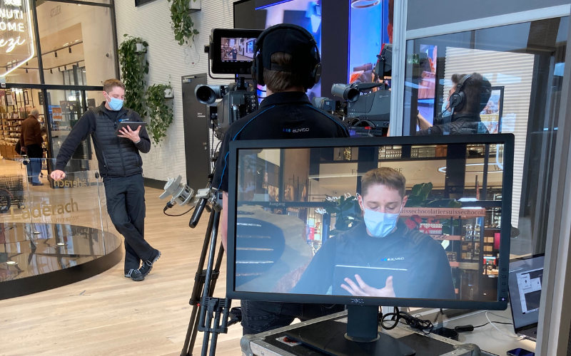 Live-Stream Läderach Chocolatier Suisse Kontrollbildschirm, Kamera mit Kameramann bei der Übertragung der Mitarbeiterinformation.
