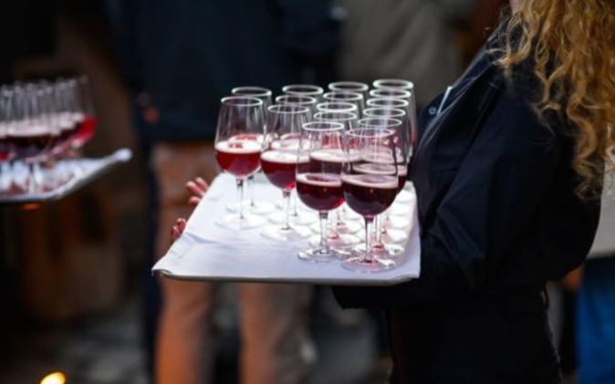 Cateringmitarbeiterin mit Tablar mit gefüllten Gläser