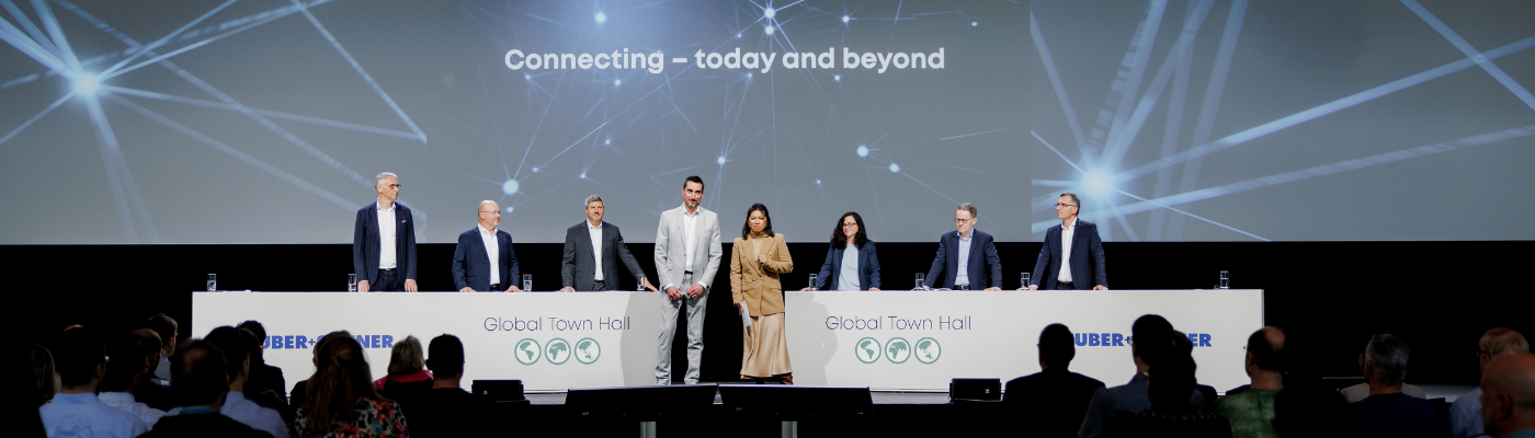 Global Town Hall Huber + Suhner AG Podium mit 8 Personen am Global Town Hall der Huber + Suhner AG