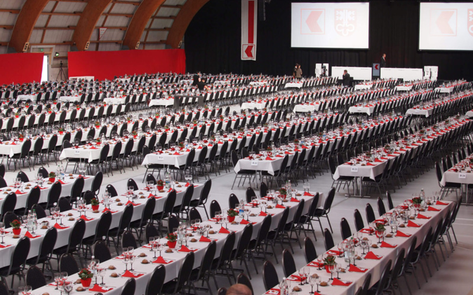 Partizipations-Versammlung der Nidwaldner Kantonalbank Halle mit vielen schön gedckten Tischen und Stühlen. Farben rot und weiss.