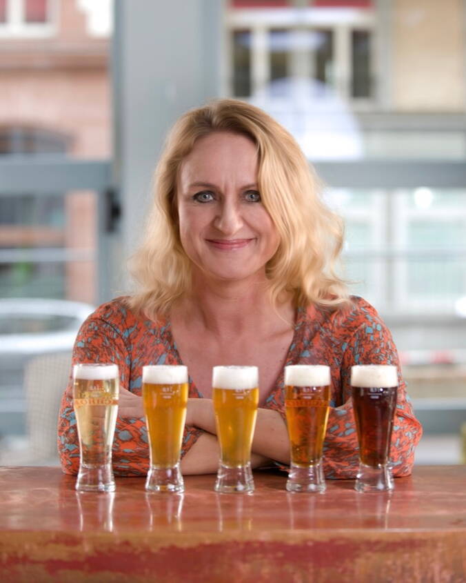 Portrait von Carmen Wyss mit fünf Biergläser vor sich. 
