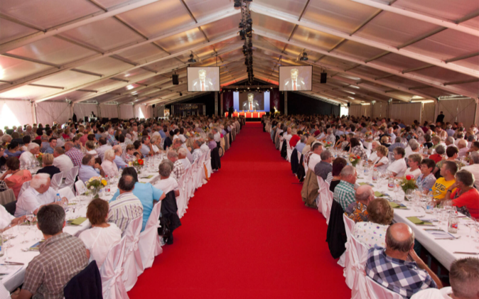 Zelt mit Gästen an gedeckten Tischen, Hintergrund Leinwand, roter Teppich. 