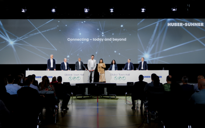 Global Town Hall Huber + Suhner AG Podium mit 8 Personen am Global Town Hall