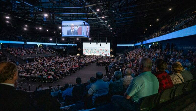 Bossard Arena in Zug an GV der Zuger Kantonalbank mit vielen Gästen. Im Hintergrund Leinwände.  