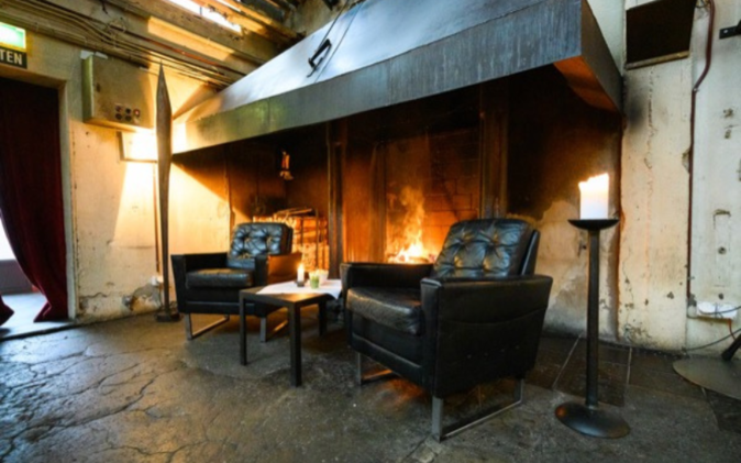 Cheminée mit Feuer und zwei Sessel.