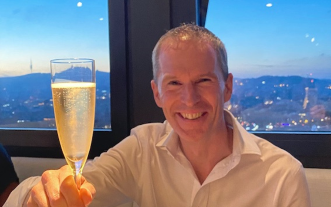 Oliver Furrer mit erhobenen Prosecco-Glas zum Anstossen auf das 15-Jahr-Jubiläum