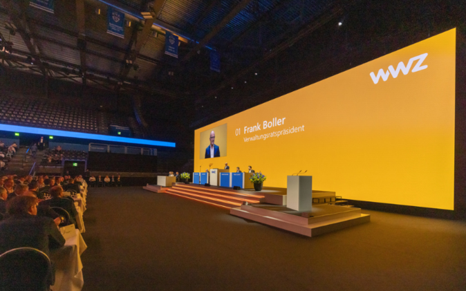 Stage with large screen in the background at the general meeting. 