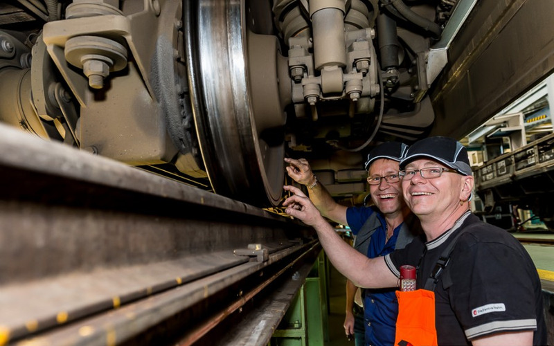Tag der offenen Tür - zb Zentralbahn AG Zwei Mitarbeitende der zb bei einer Vorführung unter einem Zugwagen.