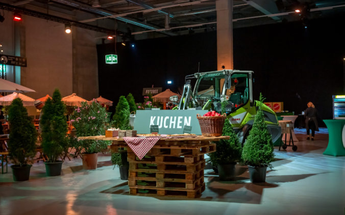 Landwirtschaftliches Streetfood-Festival in einer Halle an einem der vier Jubiläumsanlässen, Bagger mit Desserbuffet auf der Baggerschaufel. 