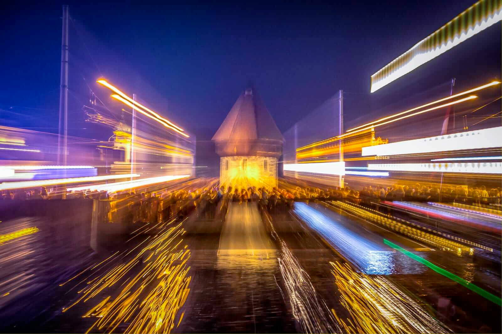 Nachtaufnahme vom Wasserturm mit vielen Leuten. 