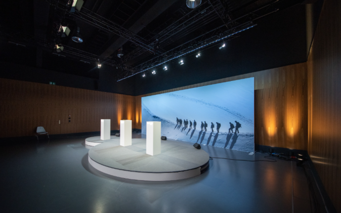 Digitale Mitarbeiterinformation Podium mit grosser Leinwand im Hintergrund.