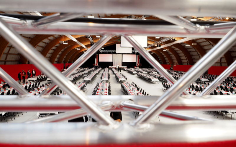 PS-Versammlung der Nidwaldner Kantonalbank Halle mit gedeckten Tischen durch ein Befestigungsmasten fotografiert.